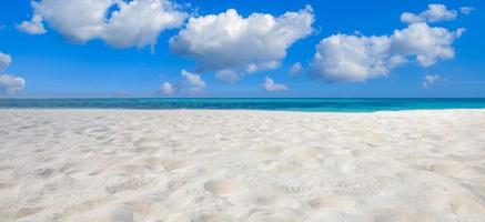 eindeloze panoramische strandscène, rustig zomerlandschap. blauwe lucht en zachte oceaangolven. abstracte strand achtergrond. wit zand, blauwe lucht en rustig tropisch strandlandschap. exotisch natuurconcept foto