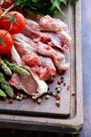 rauw vlees, lamskoteletjes met groenten op een houten bord foto