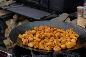 Brokken gebakken aardappelen in een grote koekenpan tijdens het straatvoedselfestival. foto