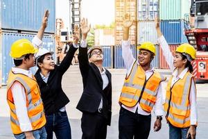 groep medewerkers en managementteam die logistieke uniformen dragen voor het exporteren van producten naar het buitenland, staan om uw handen op te steken en samen uw handen op te steken voor een harmonieuze werkervaring foto