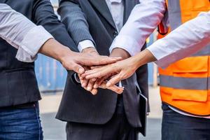 groep medewerkers en managementteam die logistieke uniformen dragen voor het exporteren van producten naar het buitenland, staan om uw handen op te steken en samen uw handen op te steken voor een harmonieuze werkervaring foto