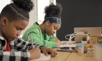 student in de internationale kleuterschool die samen een boek schrijft in de basisschoolklas, leerlingen genieten van studeren in de klas. foto