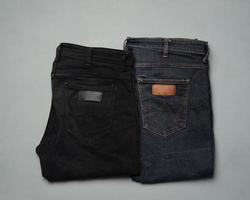 stapelt netjes gerangschikte blauwe en zwarte jeans. eigentijdse broeken worden vaak gebruikt als modekeuze voor de mensen van vandaag. jeans zijn duurzaam en niet gemakkelijk beschadigd. lange broek mockup voor ontwerpsjablonen. foto
