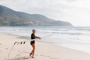 surfende vrouw met surfplank op het strand foto