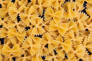 droge pasta achtergrond. sluit de rauwe farfalle pasta op een donkere achtergrond. vlak patroon. bovenaanzicht. foto