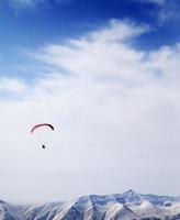 parachutist silhouet van bergen in winderige hemel foto