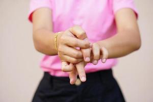 vrouw krabben arm van jeuk op lichtgrijze achtergrond. oorzaak van jeukende huid omvatten insectenbetenconcept van gezondheidszorg huid. foto