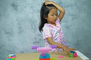 portret van een klein meisje dat aan tafel speelt met speelgoed voor demontageblokken foto