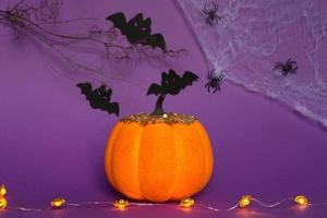 Halloween-achtergronden van witte, oranje en gouden pompoenen, spinnen en zwarte vleermuizen op een paarse achtergrond met spinnenwebben en verschrikkelijke landschappen. horror en een enge vakantie met kopieerruimte foto