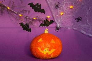 halloween achtergronden van jack lantaarn natuurlijke pompoen, spinnen en zwarte vleermuizen op een paarse achtergrond met verschrikkelijk landschap. horror en een enge vakantie met kopieerruimte foto
