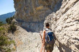 een mannelijke toerist met een rugzak loopt langs een pad in de bergen. reizen, trekking, wandelen, actieve levensstijl, sporttoerisme, gezondheidsbevordering, frisse lucht, op zoek naar avontuur. foto