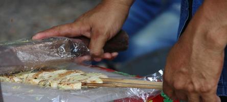 hand houdt hout vast en slaat op geroosterde banaan, thailand. foto