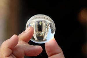 een kristallen bol houdt de vingers vast en de achtergrond wazig, het kerkbeeld reflecteert op de kristallen bol, thailand. foto