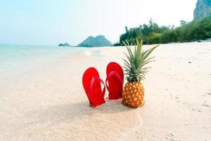 zomer strandvakantie met ananas en slippers op het strand foto