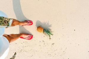 zomer strandvakantie met ananas en slippers op het strand foto