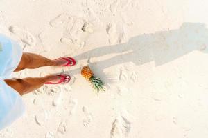 zomer strandvakantie met ananas en slippers op het strand foto