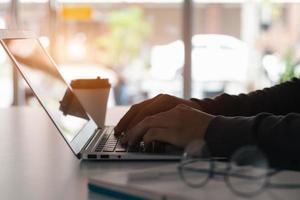 zakenman die aantekeningen maakt, vat de vergadering online samen met laptop, alleen werkend, zittend aan uw bureau. thuiswerken, close-up handen. foto