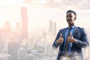 zakenmensen duimen omhoog voor acceptatie. portret van een knappe zakenman. moderne zakenman. zelfverzekerde jonge man in volledig pak die buiten staat en wegkijkt met stadsgezicht foto