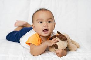 Aziatische schattige babyjongen in slaapkamer met camera kijken foto