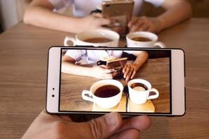 koffie in haar hand op een mobiele telefoon. foto