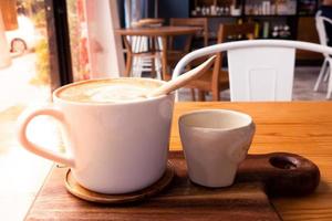 hete latte in een witte koffiekopje op een houten tafel. foto