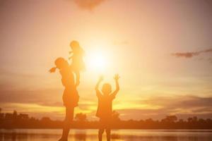 moeder moedigde haar zoon buiten aan bij zonsondergang, silhouetconcept foto