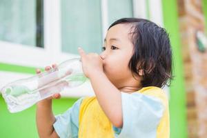 dorstig meisje drinkwater buitenshuis foto