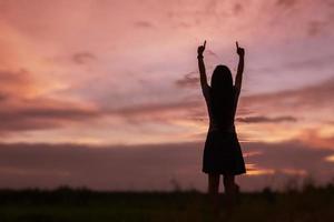 silhouet van een vrouw die bidt over een prachtige hemelachtergrond foto