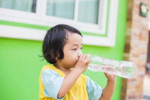 dorstig meisje drinkwater buitenshuis foto