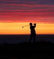 laatste rit van de golfspeler van de dag in de zonsondergang. foto