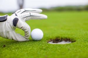 golfspeler man duwen golfbal in het gat foto