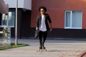 concept van jonge, snelle en mobiele manager. grappige buisinessman op skateboard in zwart pak. foto
