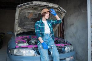 vrouwelijke monteur die auto in een garage repareert foto