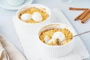 appelcrumble met ijs, lepel met streusel. ochtendontbijt op een lichtgrijze tafel foto