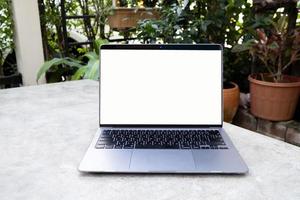 laptop met wit leeg scherm op witte tafel. online werken vanuit huis en overal werken concept. tuin huis achtergrond. foto