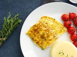 vis kabeljauw gebakken in de oven met aardappelpuree, tomaten, gezonde voeding. donkergrijze achtergrond foto