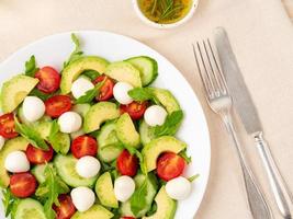 verse salade. tomaten, komkommers, rucola, mozzarella, avocado. geurige olie foto