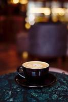 een kopje cappuccino met schuim op een marmeren tafel in een gezellig klein café. drinken met plantaardige melk, havermout, kokos foto