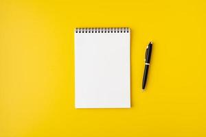 leeg spiraalvormig notitieboekje met vulpen op kleurrijke gele achtergrond, bovenaanzicht, copyspace foto