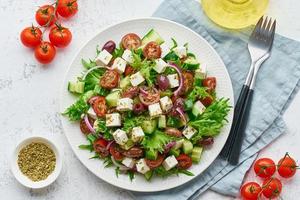 Griekse salade met feta en tomaten, op dieet zijnd voedsel op witte bovenaanzicht als achtergrond foto