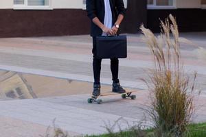 concept van jonge, snelle en mobiele manager. grappige buisinessman op skateboard in zwart pak. foto