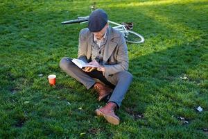 jonge mannelijke hipster leesboek in herfstpark foto