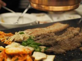 gegrild varkensvlees is op de pan in thaise stijl, thais buffet met varkensvlees, kip en ander vlees, gekookt op koperen barbecuepan, varkensgrill, bar-bq, thaise barbecue, koreaanse barbecue in thaise stijl foto