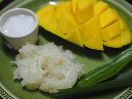 mango plakkerige rijst met kokosmelk, zoet voedseldessert op groene plaat, barracuda mango geel fruit foto