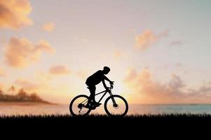 silhouet van een fietser in een mooie avondweide. ideeën voor fietsvakanties foto