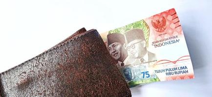 een 75.000 rupiah bankbiljet van bank indonesia onder de donkeroranje portemonnee met een grijze achtergrond. afgegeven tijdens de 75 e National Independent of Indonesia op 17 augustus 2020, periode 1945-2020. foto