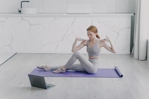 sportleraar heeft online les en stretching op mat. fysiotherapie en yoga aan huis. foto