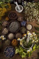 alternatieve geneeskunde, gedroogde kruiden en mortel op houten bureau achtergrond foto