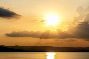 heldere mooie zonsopgang of zonsondergang aan de rivier. dramatische zonsondergang en zonsopgang hemel. oranje en gele kleuren zonsondergang. de kleurrijke zonsondergang bij de dam in thailand. succes vrijheid gelukkig leven concept. foto