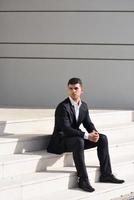 jonge zakenman in de buurt van een kantoorgebouw dragen zwart pak foto